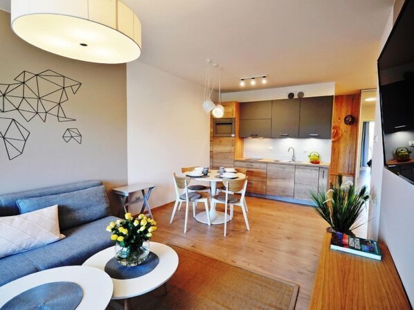 A modern living room with a sofa, coffee table, and dining area.