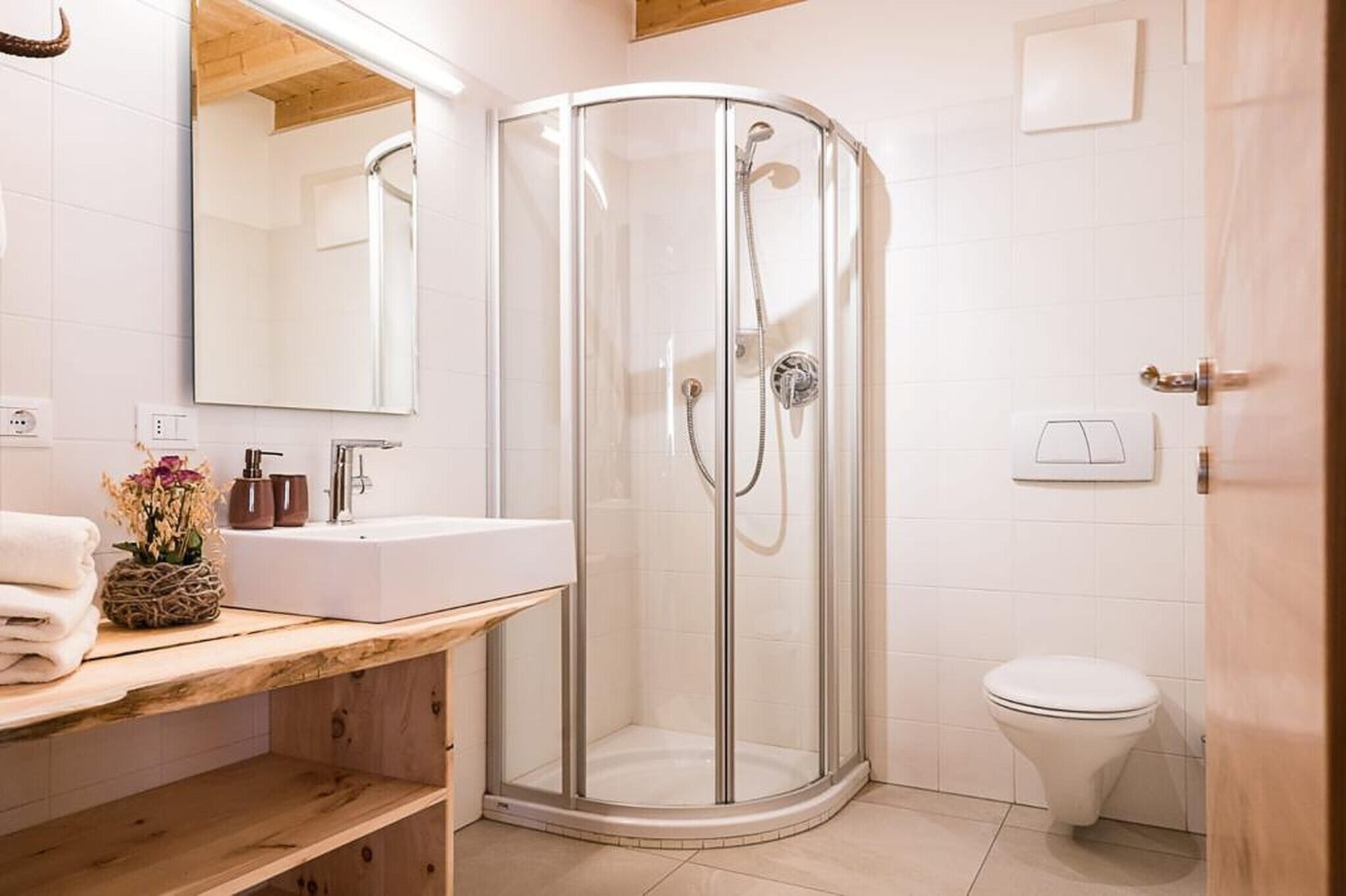 Een badkamer met een douchecabine van glas, een wit wastafelmeubel en een toilet.