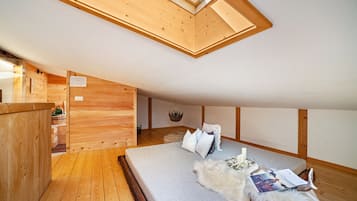 Un interior de madera con una cama, una planta colgante y un tragaluz.