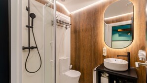 Une salle de bain moderne avec une douche à parois de verre, des toilettes blanches et un meuble-lavabo avec un miroir.