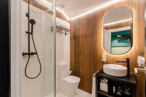 Een moderne badkamer met een douchecabine van glas, een wit toilet en een wastafelmeubel met een wastafel en spiegel.