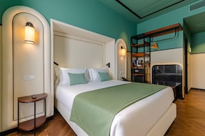 A modern hotel room with a large bed, a desk, and a bunk bed.