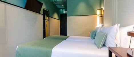 A hotel room with a bed, bedside table, lamp, and a television on a stand.