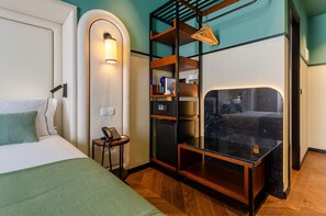 A hotel room with a bed, a desk with a phone, a minibar, and a mirror. - Nicola Rossio Hotel (Lisbon)