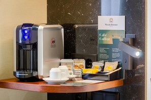 Un coin café équipé d’une machine à café, de capsules de café et d’un panneau indiquant le café du Nicola Rossio Hotel.