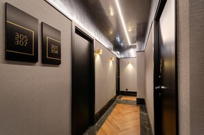 A modern hallway with black doors, numbered plaques, and a wooden floor. - Nicola Rossio Hotel (Lisbon)