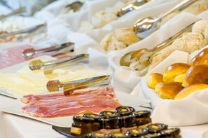 A buffet with various food items including meats, cheeses, and breads. - Nicola Rossio Hotel (Lisbon)