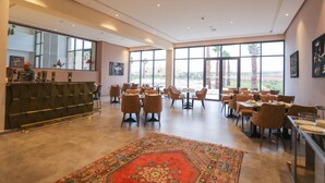 A spacious dining area with high ceilings, large windows, and a central rug. - SUMAHAN SUITES & SPA (Tameslouht)