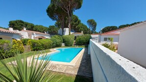 A swimming pool surrounded by a white wall, with a grassy area and trees in the background. - Typical house under the pines with swimming pool and wifi (L'Escala)
