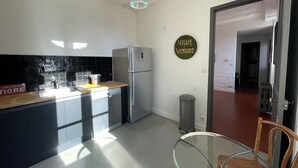 A modern kitchen with a refrigerator, a sink, and a glass table. - Center, charm, comfort, Clim, shops, restaurants, transport, outings, pkg. (Toulon)