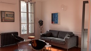 A living room with a grey sofa, two black chairs, a white coffee table, a radiator, and a painting on the wall. - Center, charm, comfort, Clim, shops, restaurants, transport, outings, pkg. (Toulon)