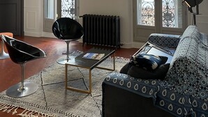 A living room with a chandelier, a radiator, a sofa, a coffee table, and a chair. - Center, charm, comfort, Clim, shops, restaurants, transport, outings, pkg. (Toulon)