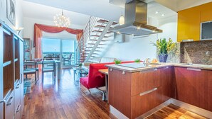 A modern kitchen with wooden cabinets, a red sofa, and a staircase leading to an upper level.