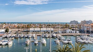 A marina with numerous boats docked, surrounded by buildings and palm trees.