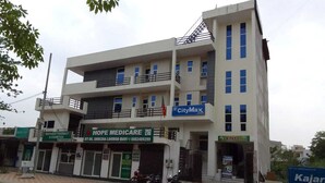 A multi-story building with various businesses including a pharmacy, a medical center, and a tiles store. - Hotel CityMax Inn (Greater Noida)