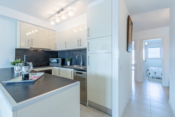 A modern kitchen with white cabinets, a dark countertop, and a built-in microwave. - 0112-PORT GREC Apartment with canal view (Empuriabrava)