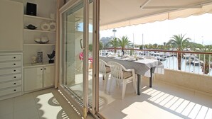 Een balkon met een tafel en stoelen, uitzicht op een jachthaven en een stadsbeeld op de achtergrond.