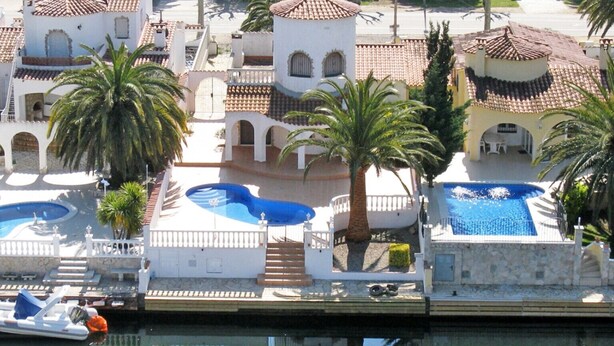 Un hôtel situé sur la côte, doté de plusieurs piscines, de palmiers et d’un port de plaisance.