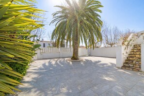 Um pátio com uma palmeira, uma escadaria de pedra e um cercado branco.