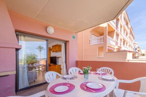 An outdoor dining area with round tables, white chairs, and pink placemats. - 0087-MIRABLAU Apartment in front of the beach (Empuriabrava)