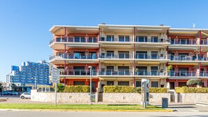 A multi-story hotel with balconies, a stone wall, and a clear blue sky. - 0087-MIRABLAU Apartment in front of the beach (Empuriabrava)