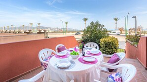 A table set for four with white chairs, a white tablecloth, and pink placemats. - 0087-MIRABLAU Apartment in front of the beach (Empuriabrava)