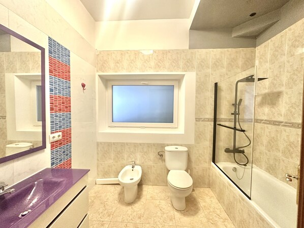 Une salle de bain moderne avec un grand miroir, un bidet, des toilettes et une douche à parois de verre.