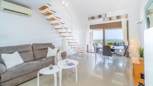 Una sala de estar moderna con una escalera, un sofá, una mesa de centro y un comedor con vistas.