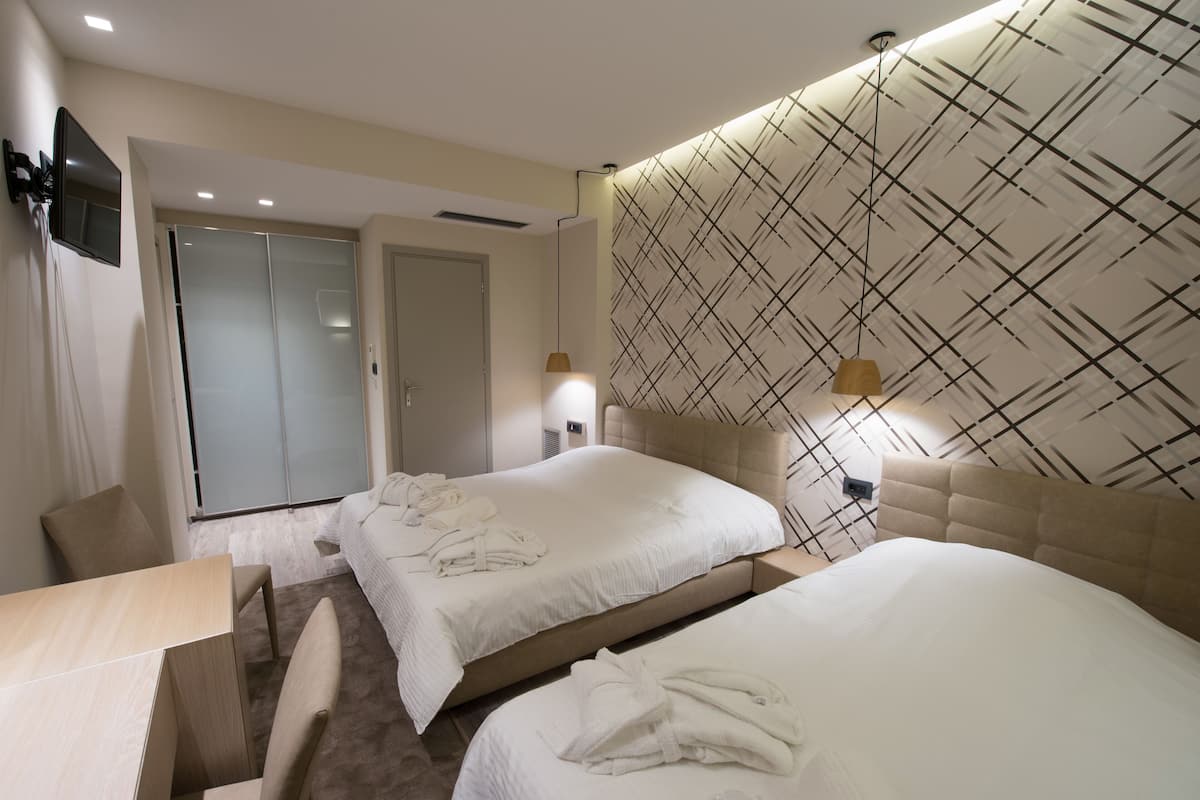 Quarto de hotel com duas camas, uma escrivaninha e uma televisão.