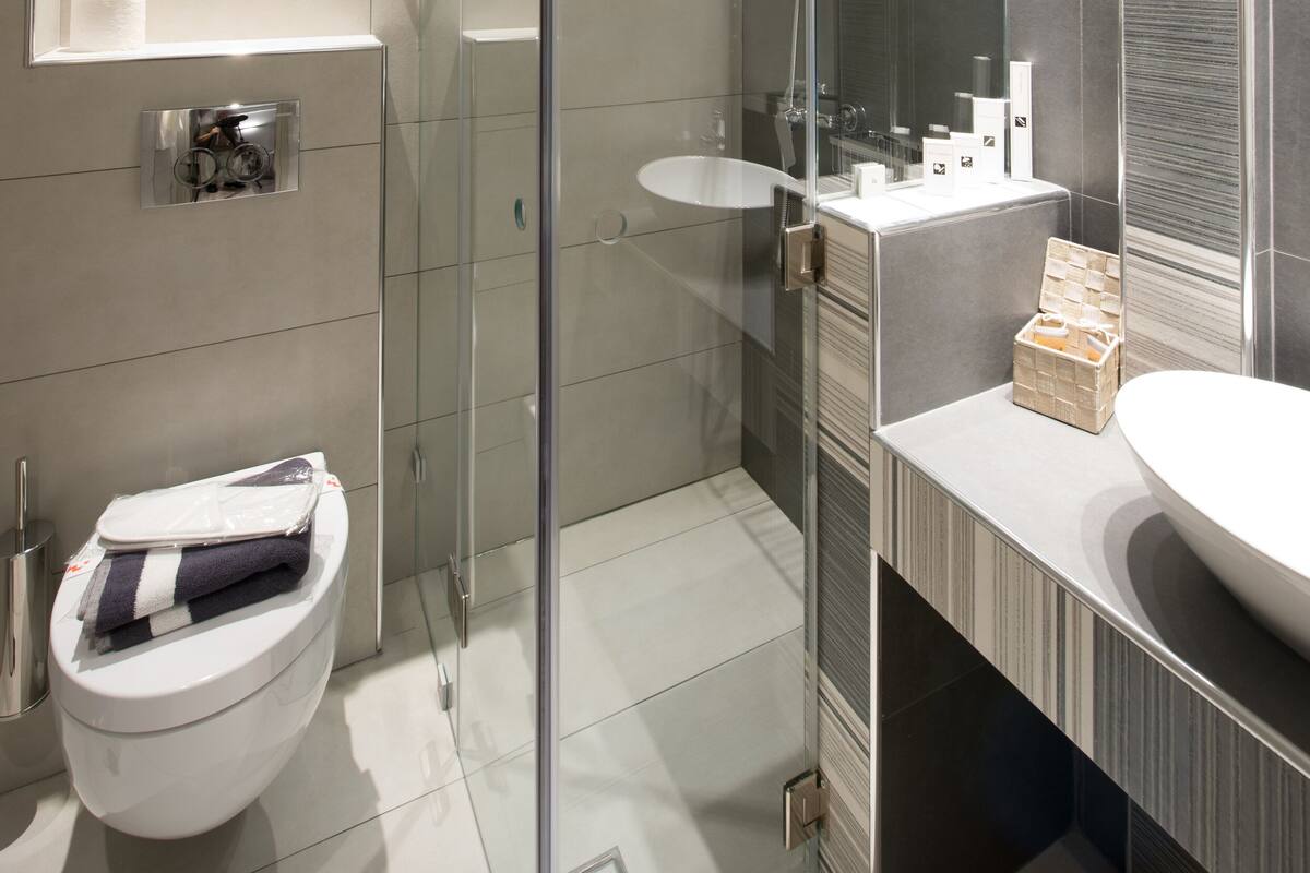 Uma casa de banho moderna com chuveiro em cabine de vidro, sanita e toucador com lavatório.