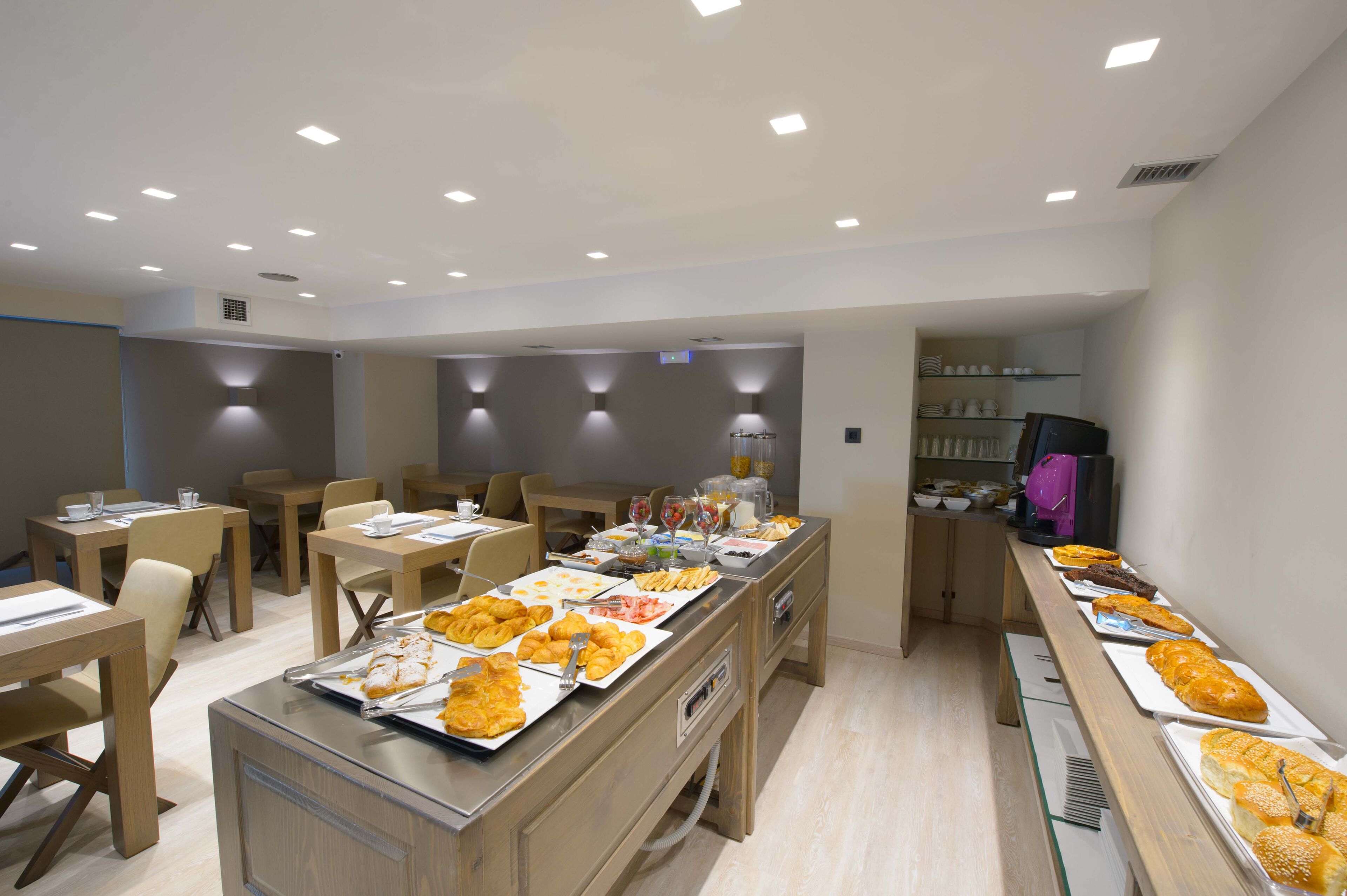 Comedor con varias mesas, sillas y un bufé con diferentes opciones de comida.