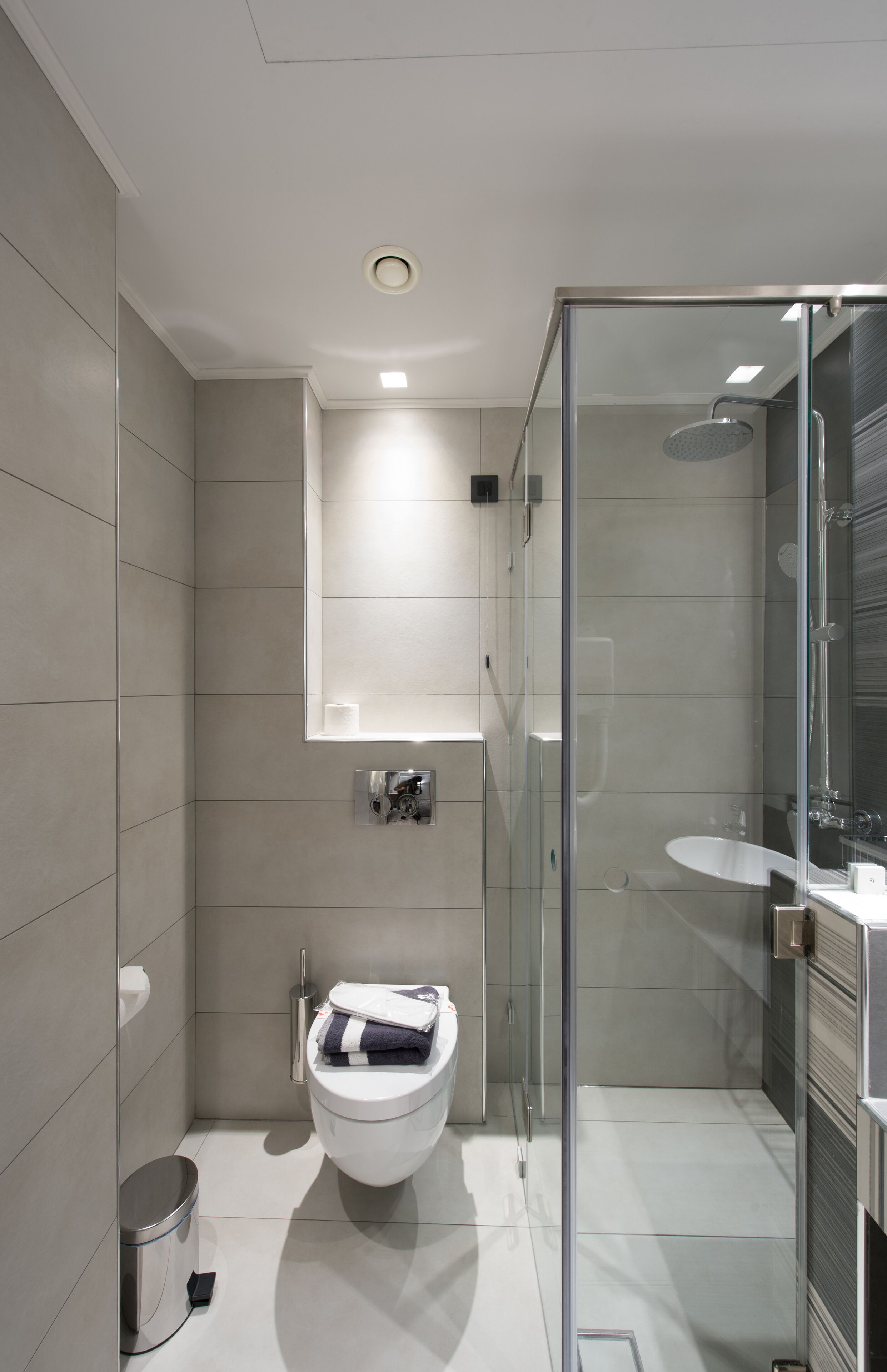 Un baño moderno con inodoro, ducha con mampara de vidrio y lavamanos.