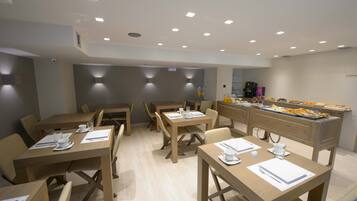 Un comedor moderno con mesas y sillas de madera, un bufé con diferentes opciones de comida y una máquina de café.