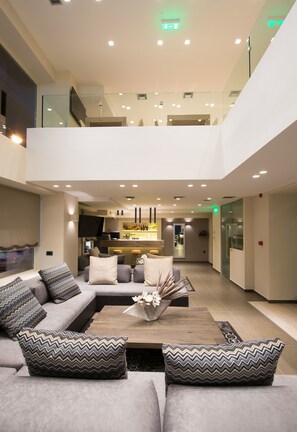 A spacious, modern living area with a sofa set, a coffee table, and a bar area in the background.