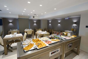 A breakfast buffet with various food items and a seating area with tables and chairs.
