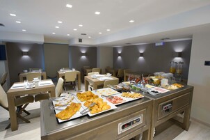 Un bufé de desayuno con diversas opciones de comida y un área de estar con mesas y sillas.