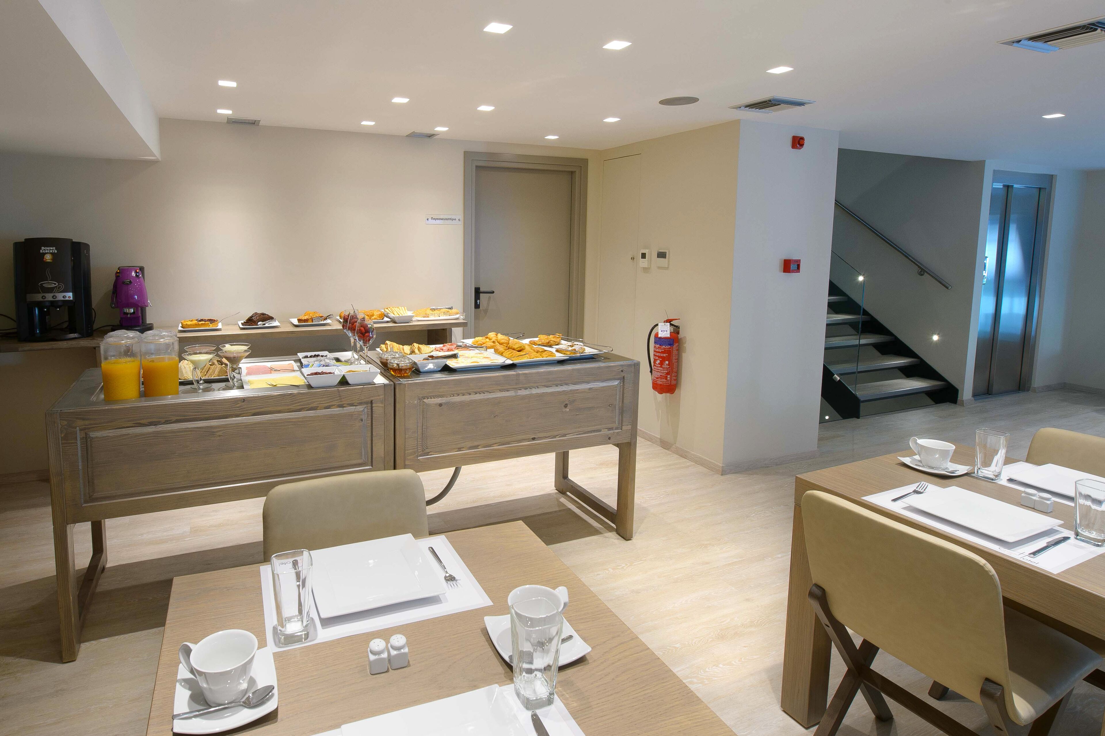 A hotel dining area with a buffet table, chairs, and a staircase.