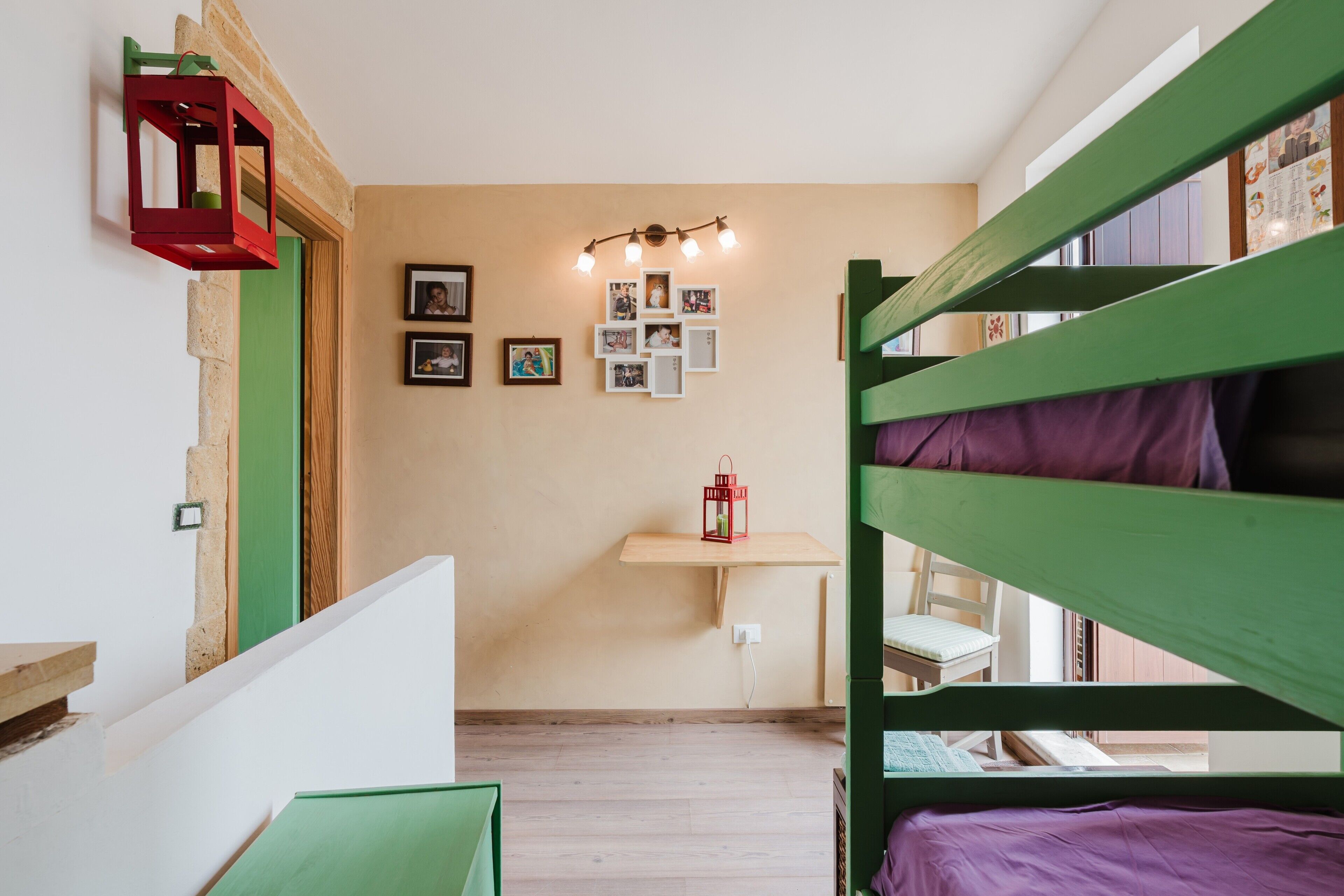 A room with bunk beds, a desk, and a wall-mounted light fixture.