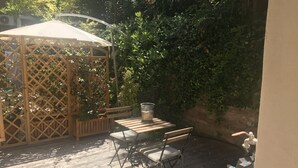 Eine Holzterrasse mit einem Pavillon, einem Tisch und zwei Stühlen.