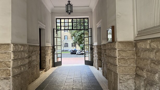 A hallway with stone walls and a tiled floor leading to a gated entrance. - Beautiful apartment within walking distance of St. Peter's (Roma)