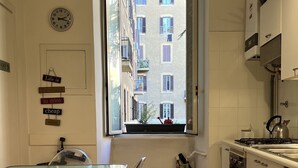A small kitchen with a window, a dining table with chairs, and a clock on the wall. - Beautiful apartment within walking distance of St. Peter's (Roma)