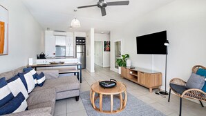 A modern living room with a sofa, coffee table, and a flat-screen TV.
