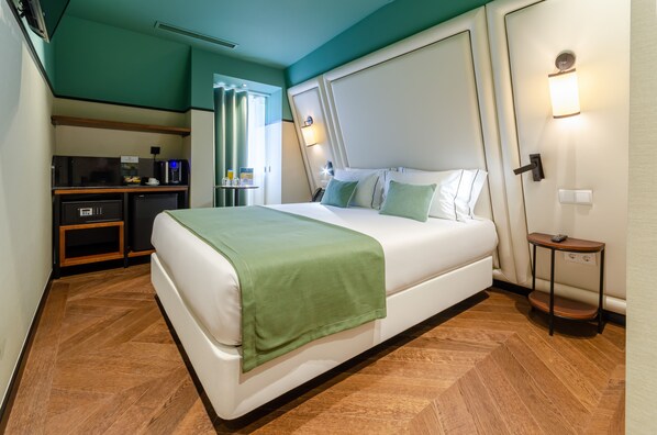 Een hotelkamer met een bed, een bureau, een koffieapparaat en een klein tafeltje.