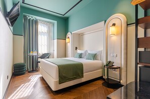 Ein modernes Hotelzimmer mit einem großen Bett, einem Schreibtisch, einem Stuhl und einem kleinen Tisch mit Telefon.