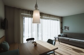 Un salon moderne avec une table à manger en bois, un canapé et un luminaire suspendu.