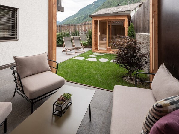 Une terrasse avec deux canapés, une table basse et un sauna en bois.