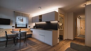 Une cuisine moderne avec un coin repas, un plancher en bois et des appareils électroménagers intégrés.
