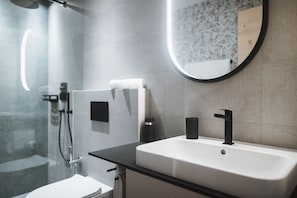 Casa de banho moderna com lavatório branco, torneira preta e espelho redondo.