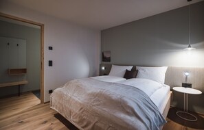 A modern bedroom with a large bed, bedside tables, a mirror, and a hanging light fixture.