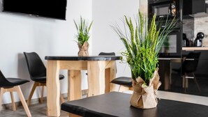 A modern dining area with a wooden table, black chairs, and a potted plant on a black table. - Casa Bombón - Country House with Private Pool & Wi-Fi – Families Only (Vejer de la Frontera)